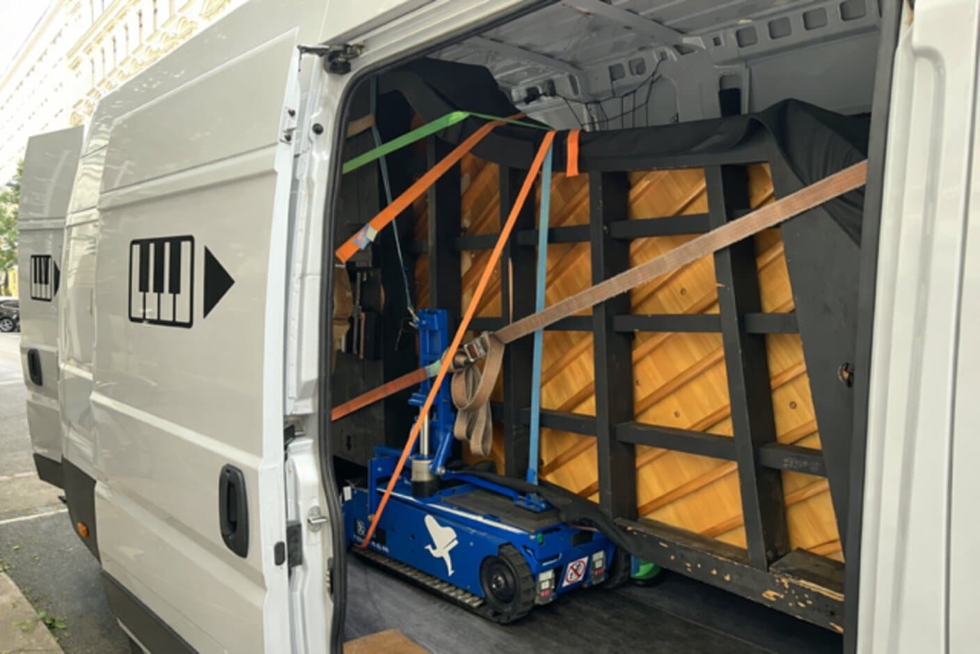 Klaviertransport in Wien: gesichertes Klavier wird auf motorisiertem Klavierroller in einen Transporter verladen